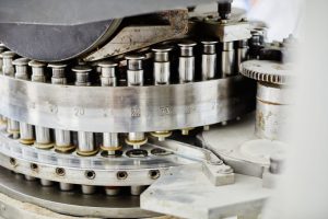 Background shot of punch tools in tablet press machine compressing powder into pills at pharmaceutical manufacturing plant, copy space